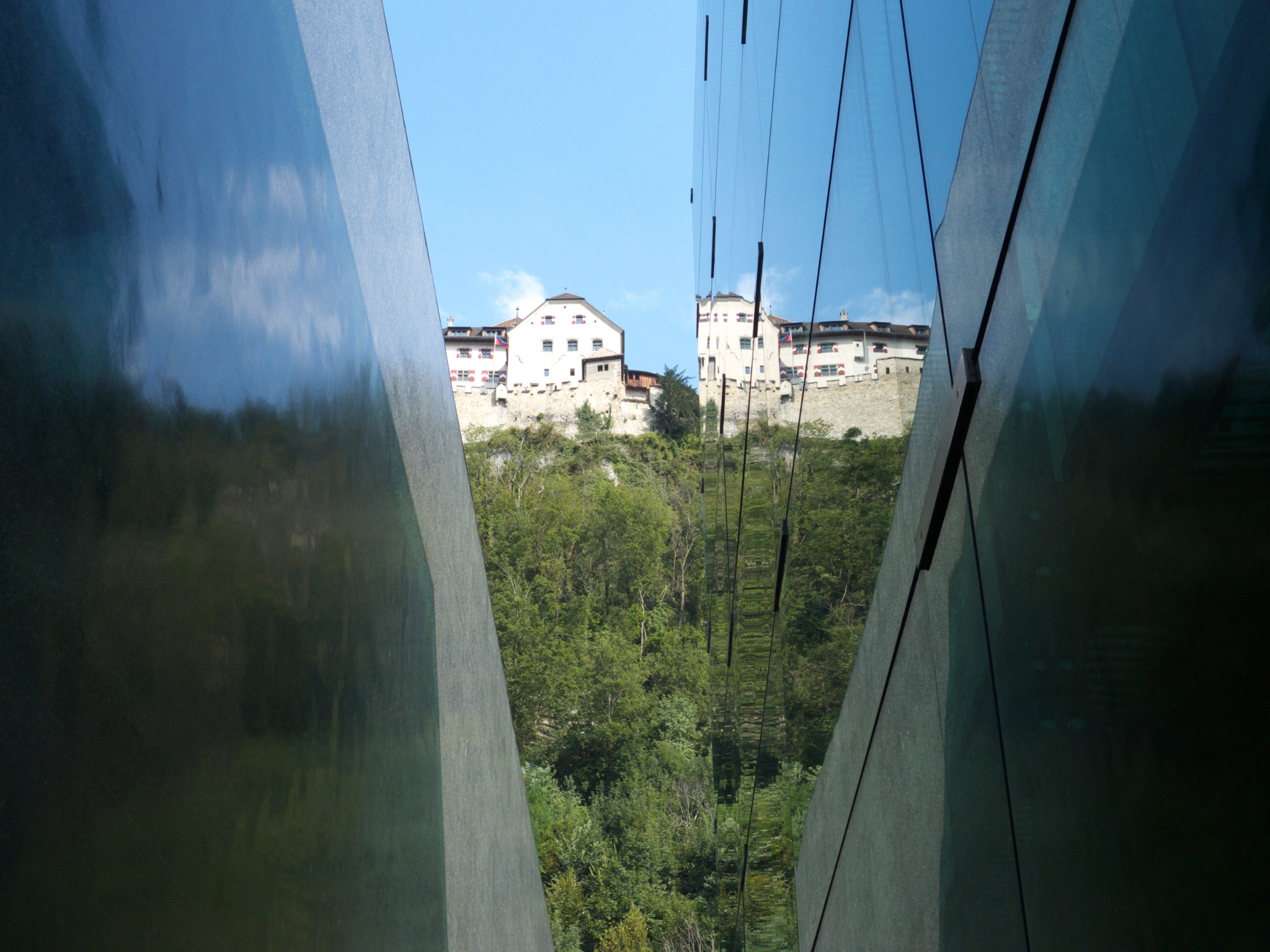 A medieval castle framed and reflected by contemporary glass architecture